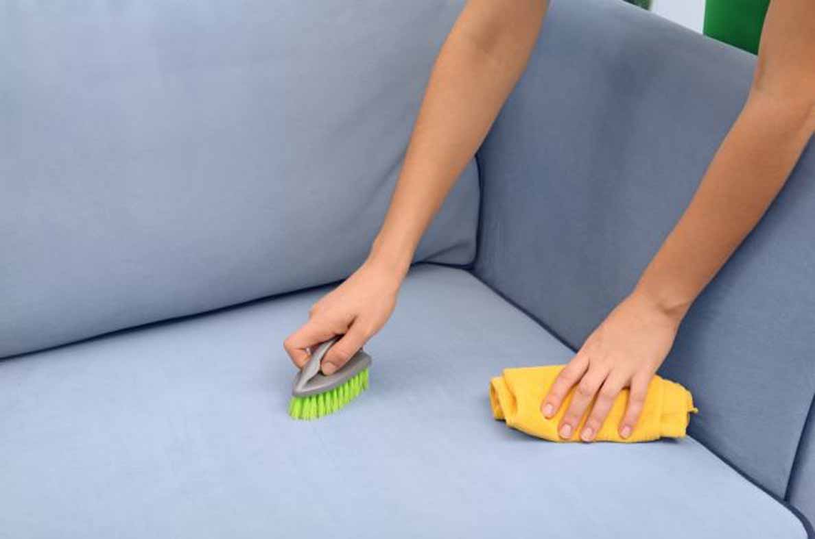 Женщина чистит диван щёткой